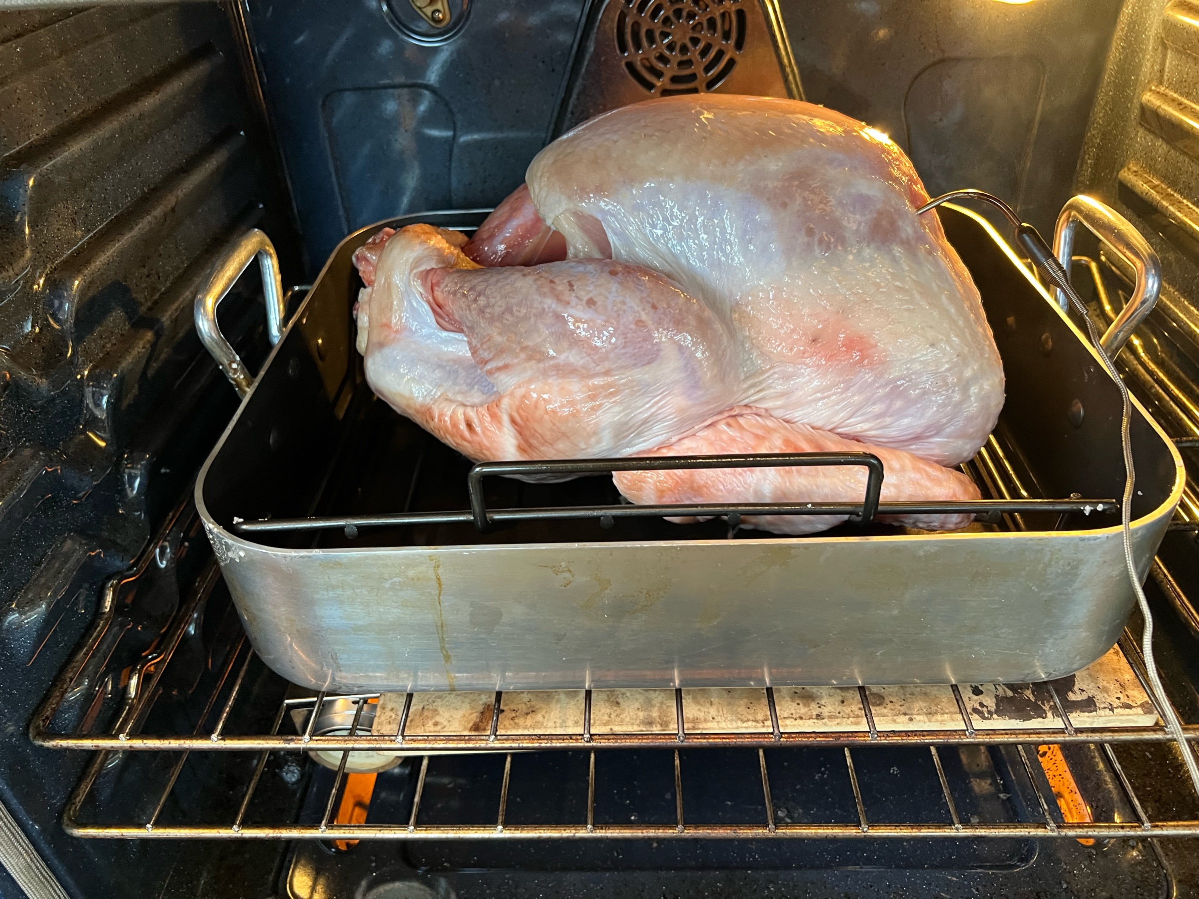 A turkey in a roasting pan, just placed in the oven