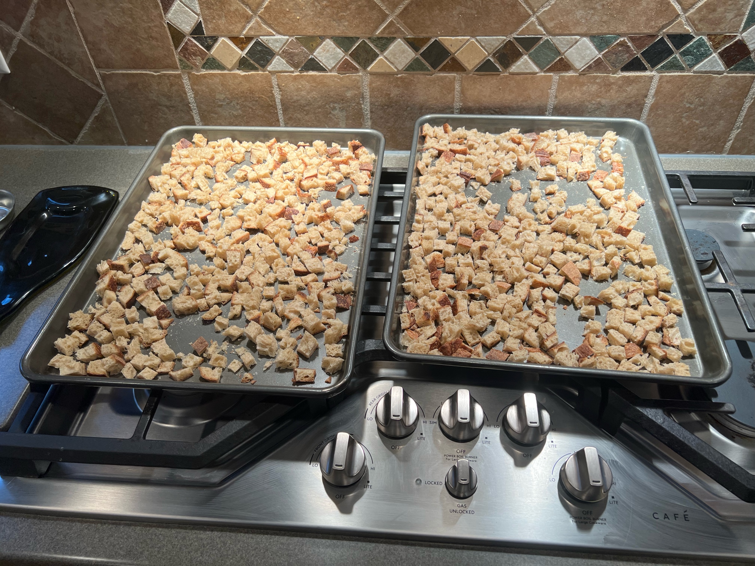 Two sheet pans of bread cubes, fresh out of the oven.