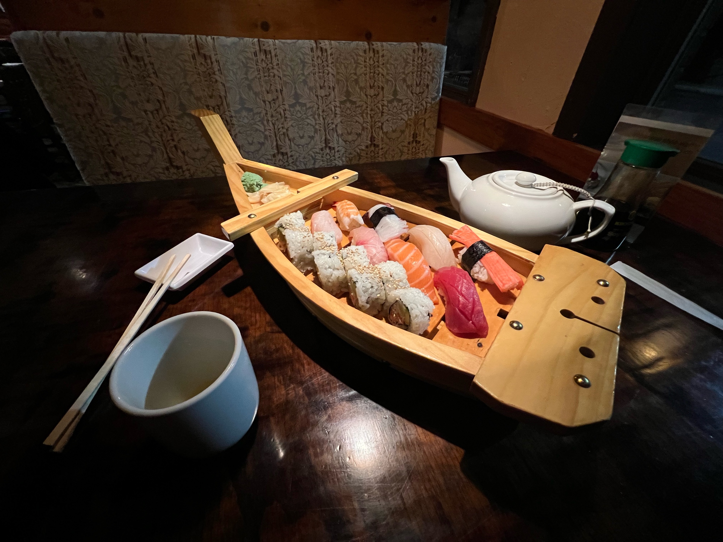 A varieity of sushi presented on a wooden vessel shaped like a boat.