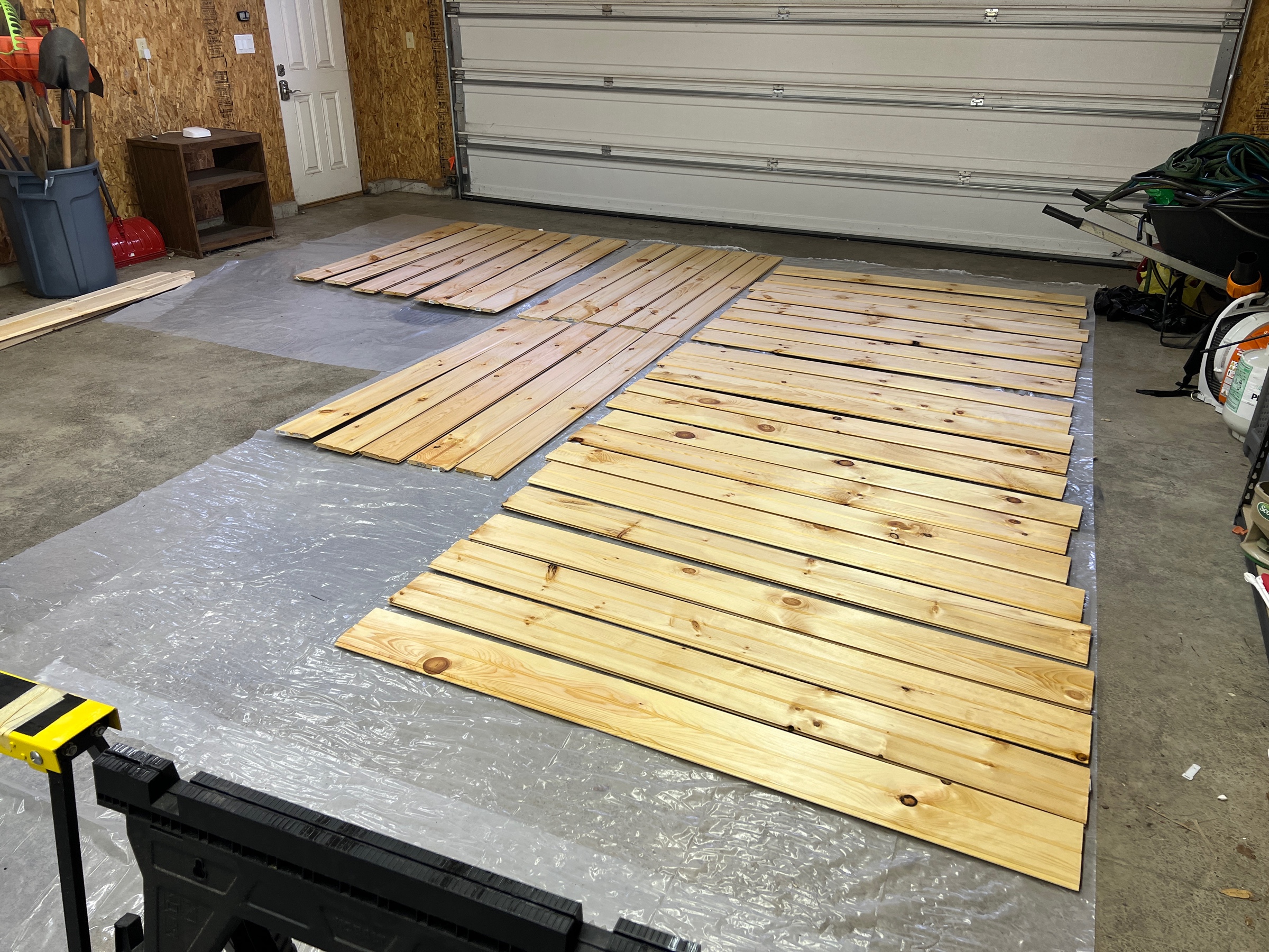 Tongue-and-groove pine boards spread out on the garage floor, drying