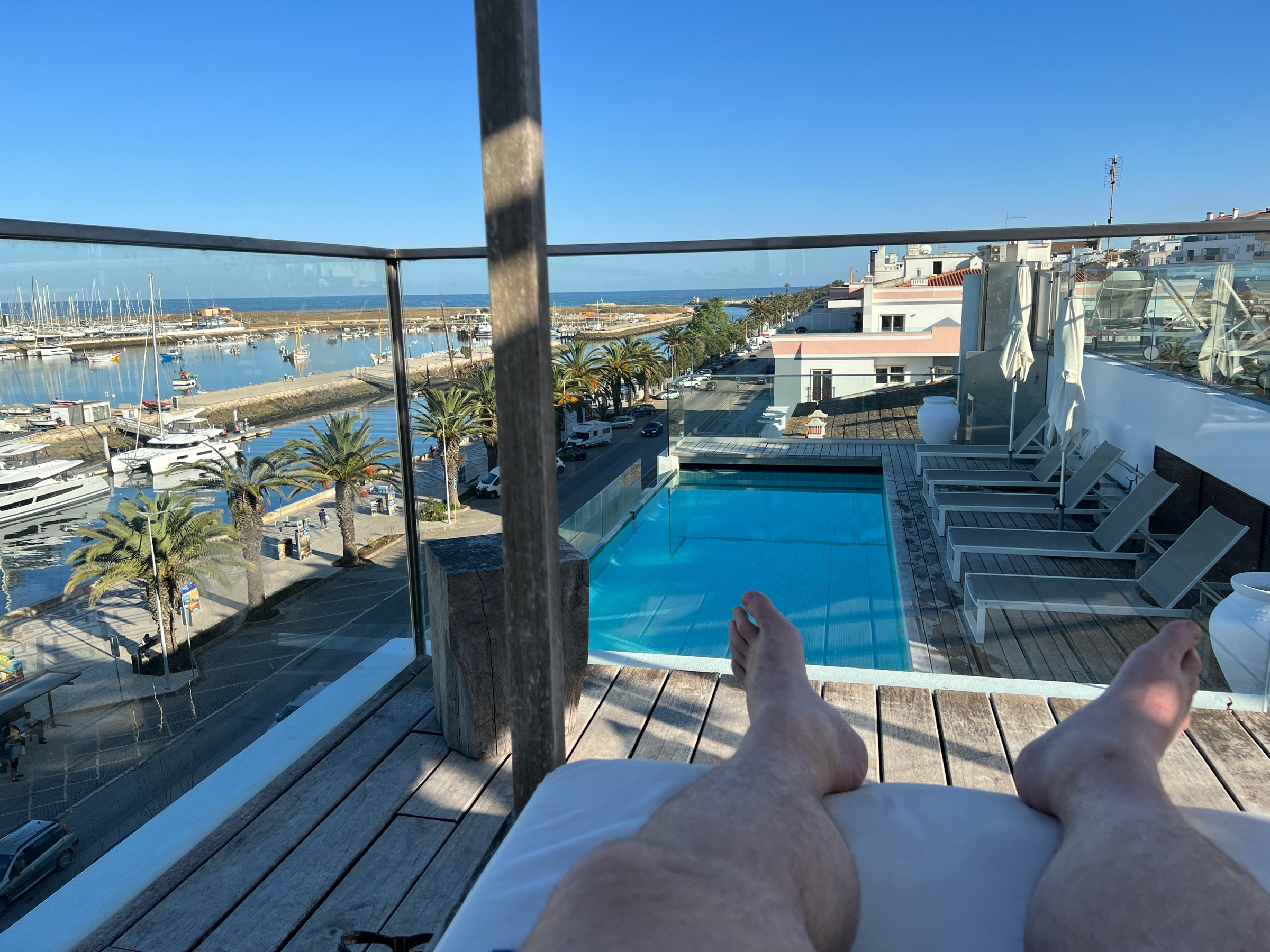 Obligatory photo of my feet in a lounge, with a rooftop pool and harbor views in the background.