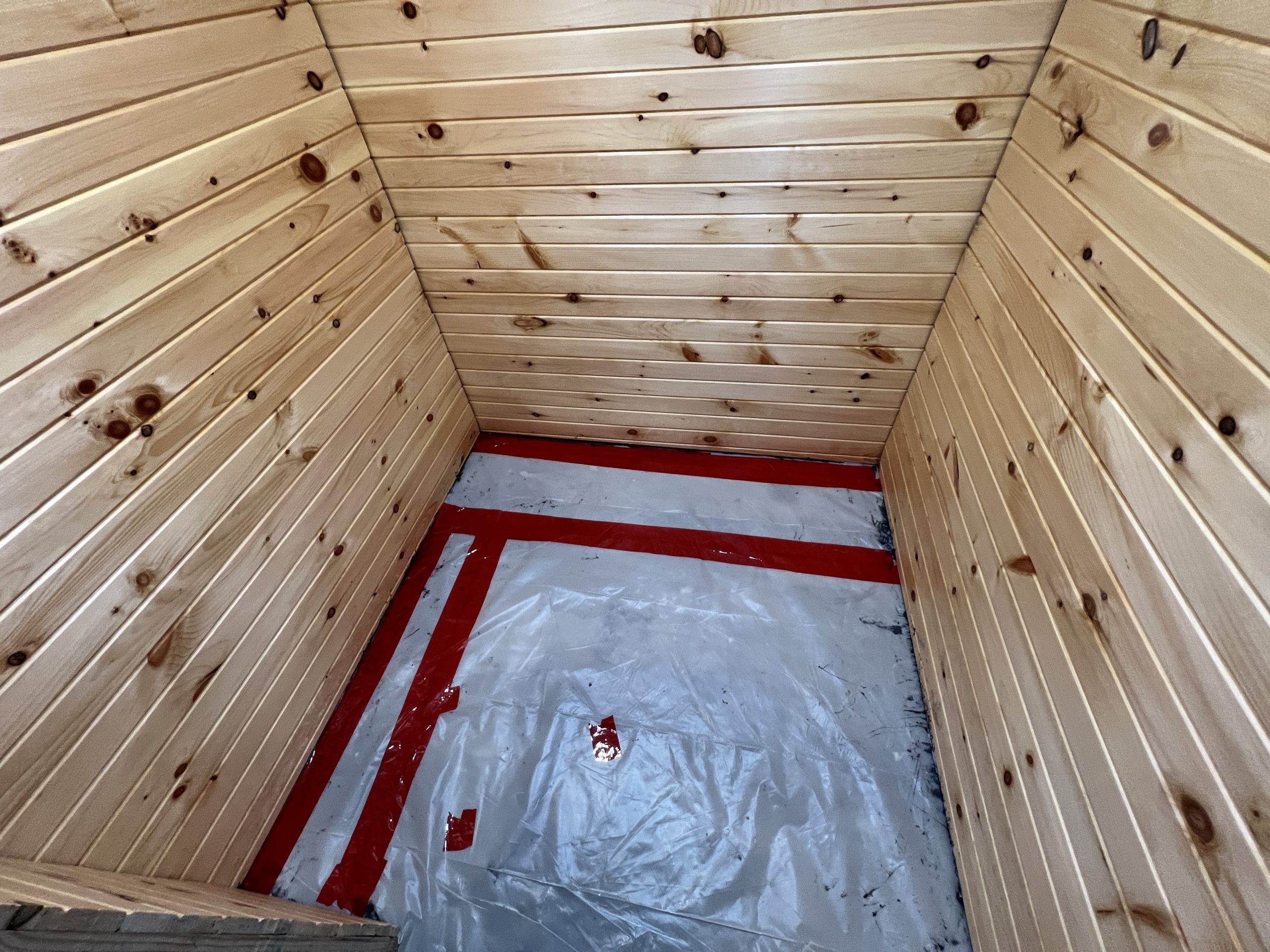 A vapor barrier made of 6 mil plastic sheeting applied to the floor, reinforced with red tape.