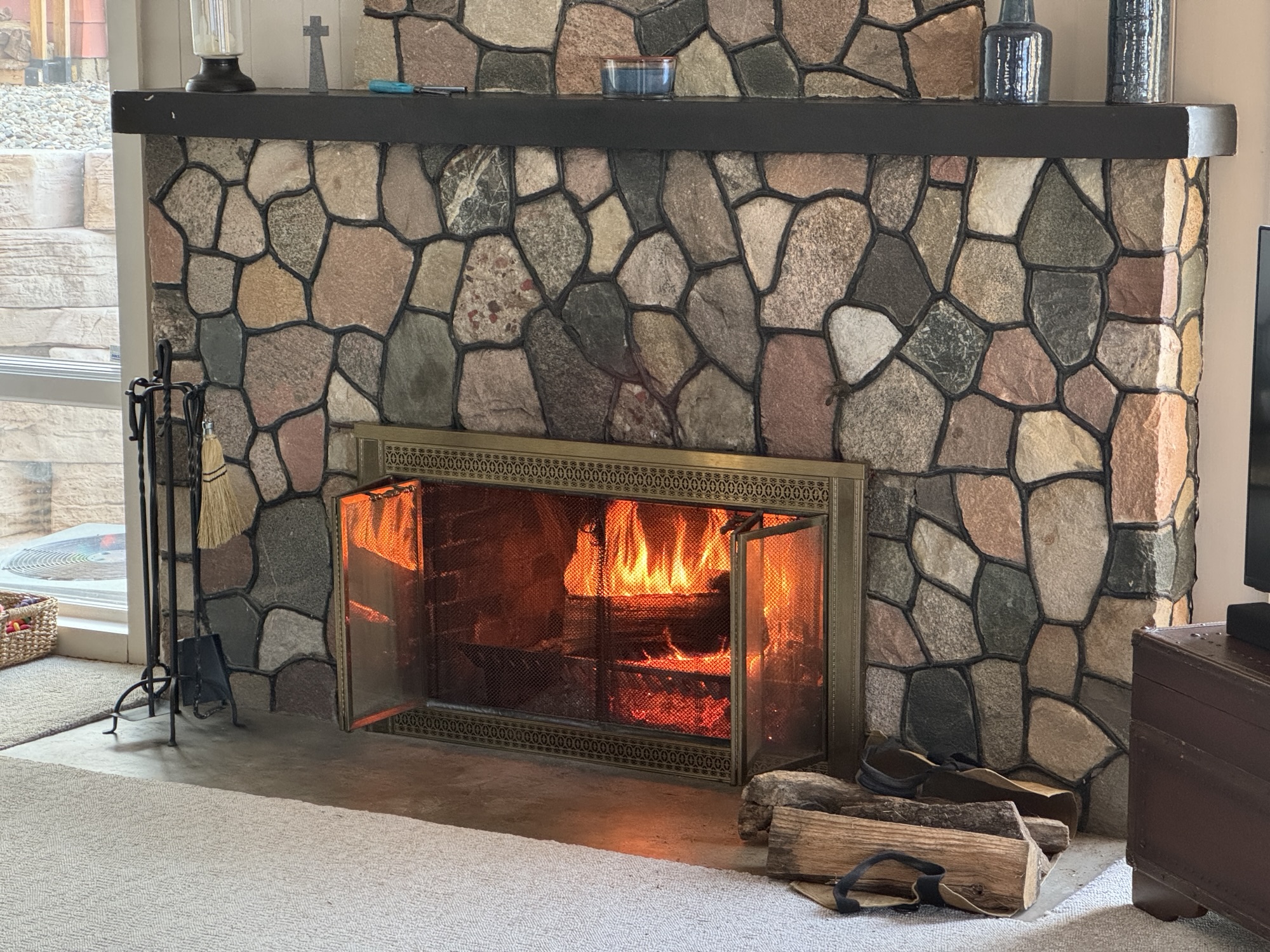 A fireplace built of fieldstones with a roaring fire.